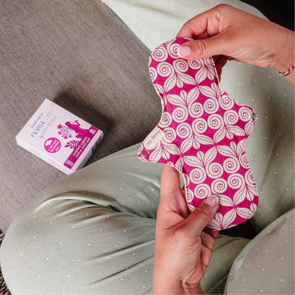 hands holding natracare eco femme reusable day pad showing organic cotton fabric and size